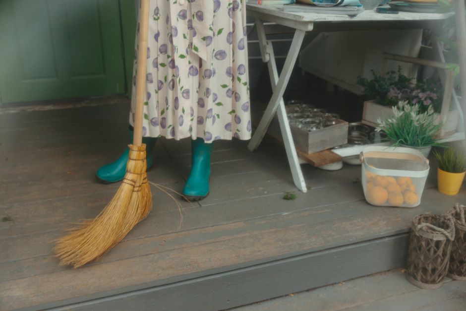 Crop unrecognizable woman in yellow rubber gloves cleaning white tiles with spray and soapy sponge
